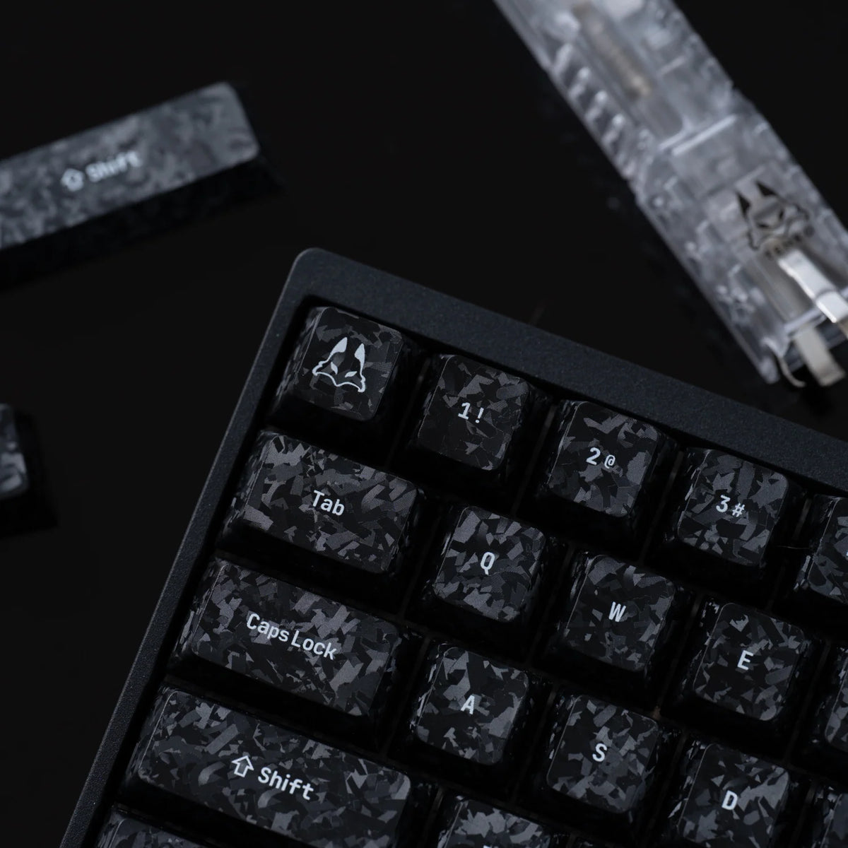 Carbon fibre textured keycaps fitted to a keyboard, close-up of the left side